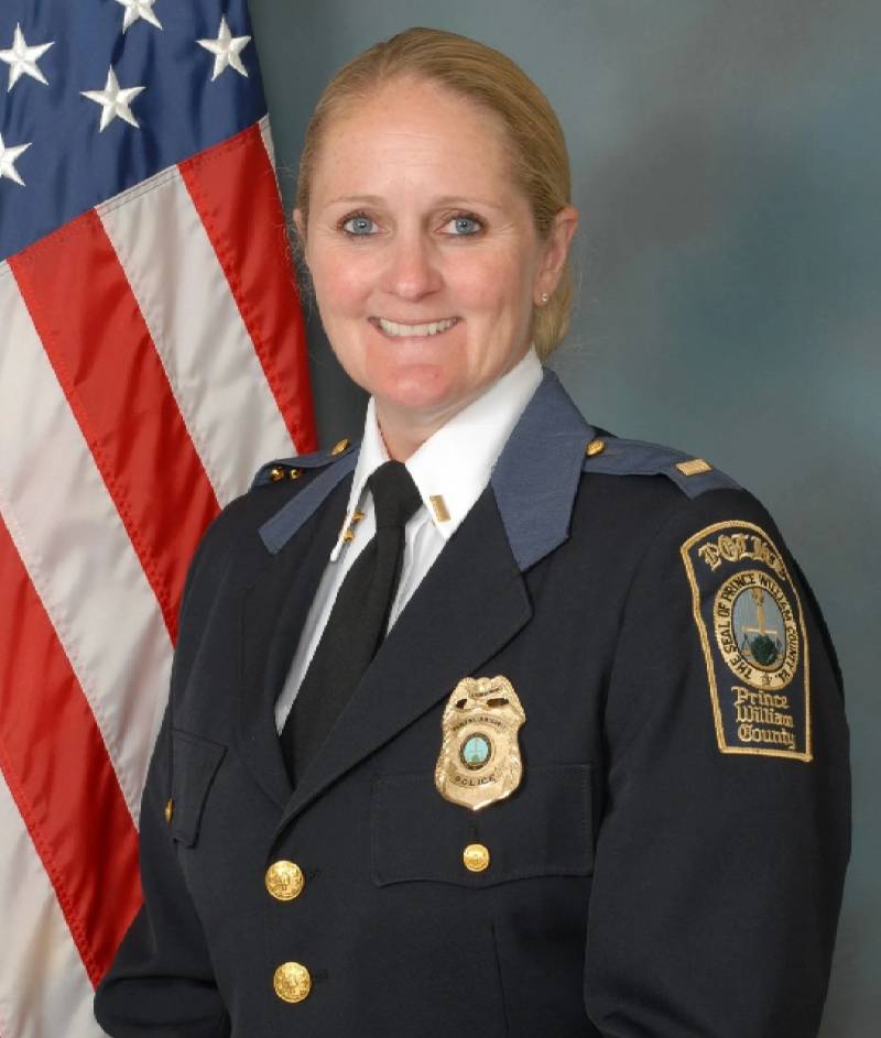 A woman in police uniform standing next to an american flag.